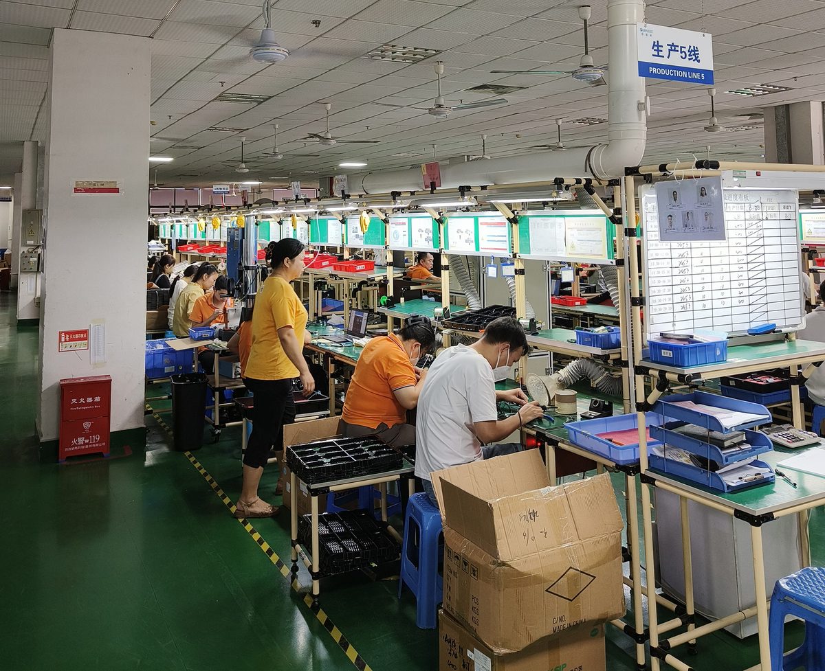 Assembly workers at benches along a production line on a Shenzhen factory floor.